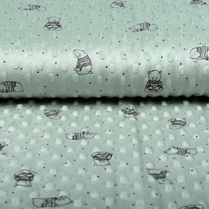 May include: A mint green fabric with a repeating pattern of black polar bears wearing sweaters. The fabric has a textured, bumpy surface.
