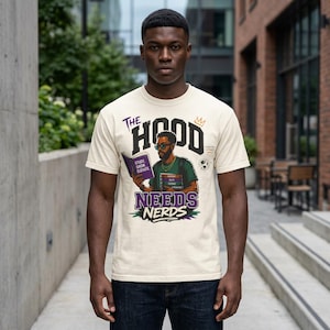 May include: Cream-colored t-shirt with a graphic that reads "The Hood Needs Nerds." The graphic features an illustration of a person wearing sunglasses and holding books. The shirt has a crew neck and short sleeves.
