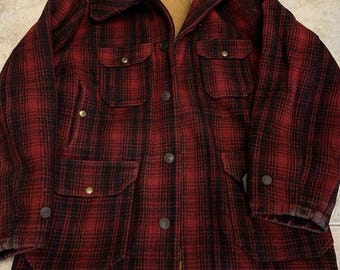 May include: A red and black plaid jacket with a button-up front, four front pockets, and a collared neckline. The jacket has a tan lining and a label on the inside collar. The jacket is made of a thick, warm material, perfect for cold weather.