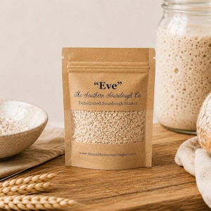 May include: A brown paper pouch containing dehydrated sourdough starter labeled "Eve" by The Southern Sourdough Co. The front features a clear window revealing the beige granular contents and the website address www.thesouthernsourdoughco.com.