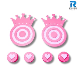 May include: Pink and white target-shaped decorations with a crown design. The targets have concentric circles and are topped with a crown of hearts. Smaller, round pink decorations with heart shapes are also visible. The image includes the text "RODGERS DESIGN & PRINT".