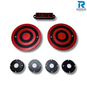 May include: A collection of black and red circular trivets and small black and white coasters. The trivets feature concentric circles, and the coasters have a white centre. A black rectangle with "180°C" is also included.