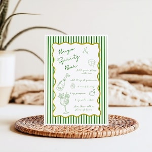 May include: A printable recipe card with green and gold stripes. The card has a recipe for a Hugo Sprity Bar cocktail. The recipe includes ingredients like St. Germain, mint leaves, prosecco, soda water, and a lime slice.