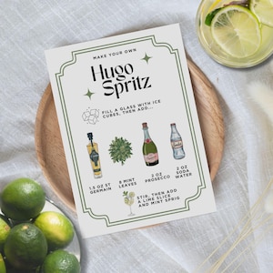 May include: A recipe card for a Hugo Spritz cocktail, featuring illustrations of ingredients like St. Germain, mint leaves, Prosecco, and soda water. The card is on a wooden tray, with limes and a glass of the cocktail in the background.