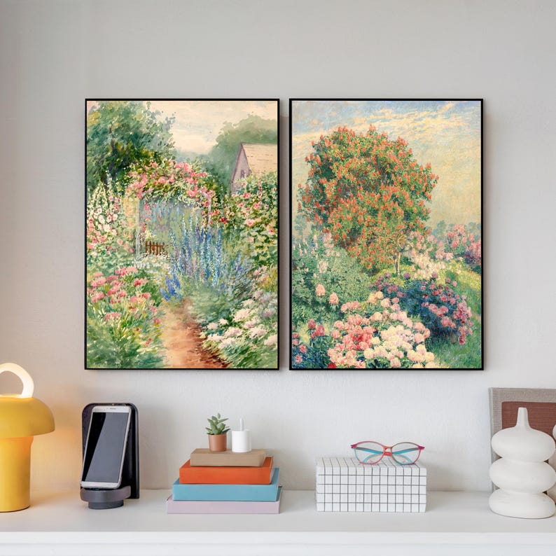 May include: Two framed watercolor paintings depicting lush gardens with vibrant flowers and foliage. The left painting shows a path leading through a garden with a small house in the background. The right painting shows a garden with a large tree in the center.