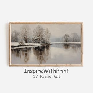 May include: A framed landscape painting depicts a serene winter scene. Snow-covered trees line the water's edge, reflecting in the calm water. The artwork has a neutral color palette with a light brown frame. The text "InspireWithPrint" and "TV Frame Art" are at the bottom.