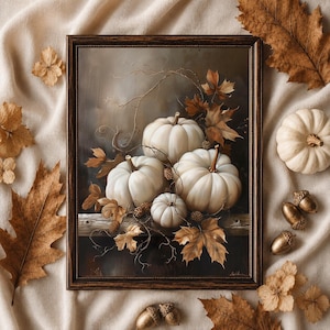 Puede incluir: Una pintura al óleo enmarcada que representa cuatro calabazas blancas dispuestas sobre un borde de madera, rodeadas de hojas de arce marrones secas y bellotas pequeñas. La obra tiene un fondo oscuro y un marco de madera marrón.