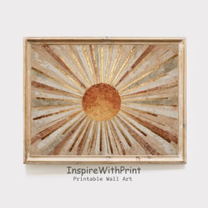 May include: A framed wall art print featuring a sunburst design. The artwork has a warm color palette with shades of brown, gold, and beige. The sun's center is a darker brown, with gold rays emanating outwards. The text "InspireWithPrint Printable Wall Art" is at the bottom.