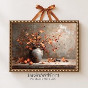 Könnte beinhalten: Ein gerahmter Kunstdruck mit einer dunkelgrauen Vase, gefüllt mit herbstlichen Zweigen, orangefarbenen Blättern und dunklen Beeren. Drei kleine orangefarbene Früchte liegen neben herabgefallenen Blättern. Der Rahmen ist goldfarben mit Perlenrand.