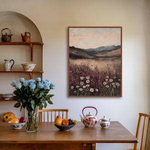 Pode incluir: Uma pintura emoldurada de uma paisagem com um campo de flores silvestres em primeiro plano e colinas onduladas ao fundo. O c&eacute;u &eacute; de um rosa e azul suave, e o sol se p&otilde;e &agrave; dist&acirc;ncia.
