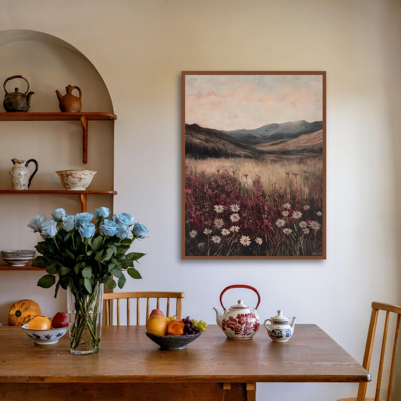 Pode incluir: Uma pintura emoldurada de uma paisagem com um campo de flores silvestres em primeiro plano e colinas onduladas ao fundo. O c&eacute;u &eacute; de um rosa e azul suave, e o sol se p&otilde;e &agrave; dist&acirc;ncia.