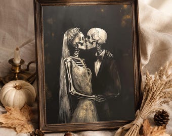 May include: A framed art print featuring a black and white illustration of two skeletons kissing. One skeleton wears a bridal veil and floral crown, while the other wears a tuxedo jacket and bow tie. The artwork is set against a dark background.