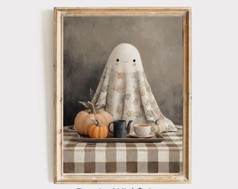 May include: A framed print featuring a friendly ghost character draped in a floral patterned sheet. The ghost sits behind a tray with pumpkins, a teapot, and a teacup on a checkered tablecloth. The text "InspireWithPrint Printable Wall Art" is at the bottom.