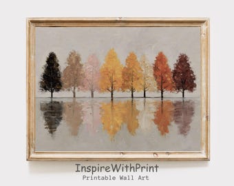 May include: A framed painting depicts a row of trees in autumn colors reflected in water. The trees range from dark brown to yellow and orange, set against a gray sky. The frame is a light gold color. The text "InspireWithPrint Printable Wall Art" is at the bottom.