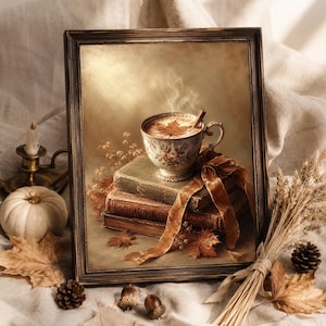 May include: A framed wall art print depicting a floral teacup filled with a warm beverage, a cinnamon stick, and a maple leaf garnish. The cup rests on a stack of three vintage books tied with a brown velvet ribbon, surrounded by autumn leaves.