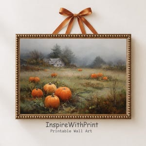 May include: A rectangular wall art print in a beaded gold frame, suspended by a brown satin ribbon. The artwork depicts a misty, autumnal landscape with a small house in the distance and several bright orange pumpkins scattered across a grassy field.
