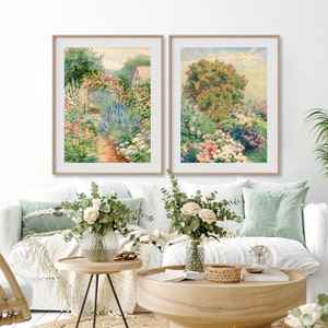 May include: Two framed watercolor paintings depicting lush gardens with vibrant flowers and greenery. The paintings are hung on a white wall above a white couch with green throw pillows.
