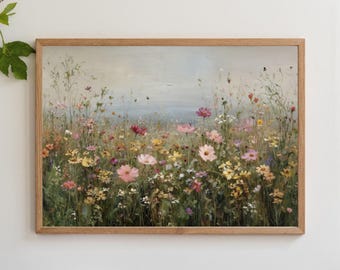 Puede incluir: Una impresión enmarcada de un campo de flores silvestres en tonos rosa, amarillo y rojo. La obra de arte tiene un estilo suave y pictórico con un fondo de cielo azul claro. El marco es de madera clara.