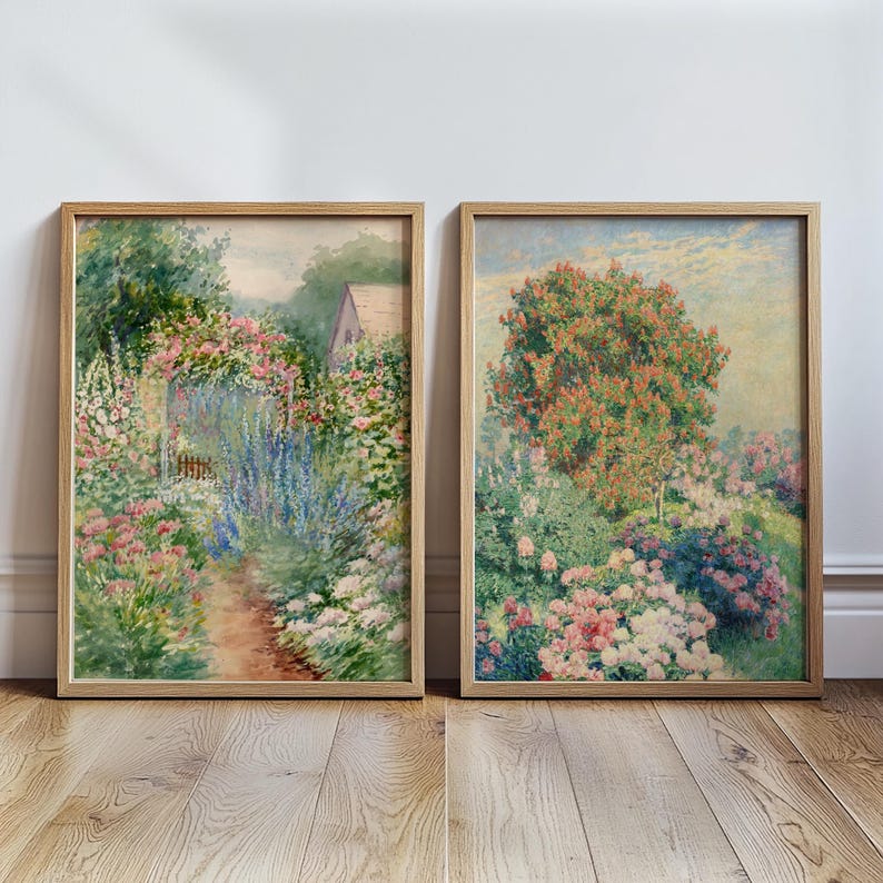 May include: Two framed watercolor paintings depicting lush gardens. The first painting shows a path winding through a garden with a small cottage in the background. The second painting shows a garden with a large tree in the center.
