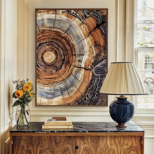 May include: A framed print of a tree trunk cross-section with concentric rings in shades of brown, gray, and black. The print is hanging on a wall above a wooden dresser with a black marble top.