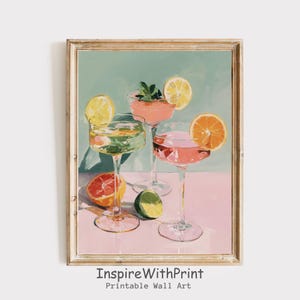 Könnte beinhalten: Ein gerahmter Druck mit drei Cocktailgläsern mit bunten Getränken und Fruchtgarnituren. Das Kunstwerk enthält Zitronen-, Orangen- und Limettenscheiben mit einem Minzzweig. Der Hintergrund ist ein weiches Grün und Rosa, mit dem Text "InspireWithPrint" unten.