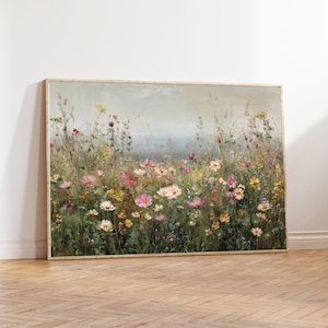 以下が含まれることがあります： ピンク、黄色、白の色合いの野草が咲き乱れる風景を描いた額入りのプリント。柔らかく絵画的なスタイルで、背景には薄い青色の空が描かれています。フレームは明るい木の色です。