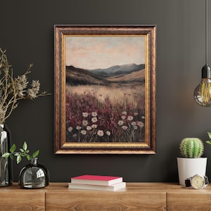 Pode incluir: Uma pintura de paisagem emoldurada que retrata um campo de flores silvestres em um vale com montanhas ao fundo. O c&eacute;u &eacute; de um rosa e azul suaves, e as flores s&atilde;o uma mistura de branco e rosa.