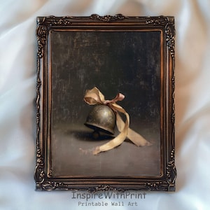 Può includere: Stampa incorniciata con una natura morta di una piccola campana antica con un nastro beige. La campana è color bronzo e il nastro ha una tonalità rosa. La cornice è ornata con una finitura bronzo scuro. Il testo "InspireWithPrint Printable Wall Art" è in basso.