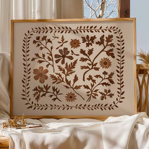 May include: A framed print with a brown floral design on a white background. The design features various flowers and leaves in a repeating pattern. The frame is made of wood and has a light brown finish.