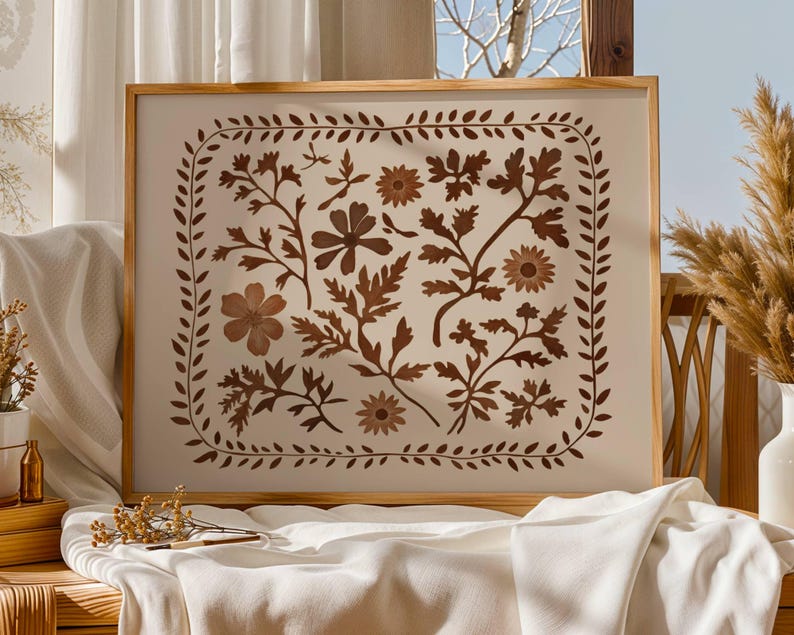 May include: A framed print with a brown floral design on a white background. The design features various flowers and leaves in a repeating pattern. The frame is made of wood and has a light brown finish.