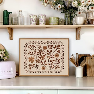 May include: A framed print with a beige background and a brown floral design. The design features a variety of leaves and flowers in a repeating pattern.