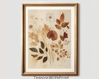 May include: A framed botanical print featuring a watercolor illustration of dried leaves and stems in shades of brown and beige. The artwork is set against a cream-colored background and framed in a gold-colored frame. The text "InspireWithPrint Printable Wall Art" is at the bottom.