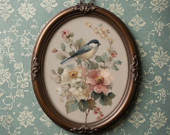 Puede incluir: Una impresión enmarcada de forma ovalada que presenta un pájaro azul y blanco posado en una rama florida. La obra de arte muestra flores rosas, blancas y amarillas suaves con hojas verdes. El marco es de color bronce oscuro con detalles ornamentados.