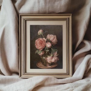K&ouml;nnte beinhalten: Ein gerahmtes Gem&auml;lde eines Strau&szlig;es rosa Pfingstrosen in einer gr&uuml;nen Vase auf einem braunen Tisch. Das Gem&auml;lde hat einen dunklen Hintergrund und ist in einem hellen Holzrahmen gerahmt.