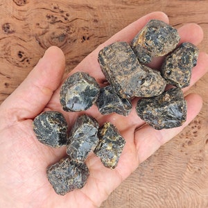 May include: A collection of dark amber stones with a black and brown color variation. The stones are rough and have a natural, unpolished look.