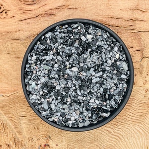 Puede incluir: Un cuenco negro lleno de pequeñas piedras grises y negras.