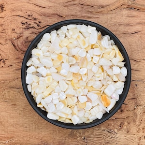 Puede incluir: Un cuenco negro lleno de virutas de concha iridiscentes blancas y crema.