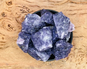 May include: A close-up of a bowl filled with rough, purple and white amethyst crystals.