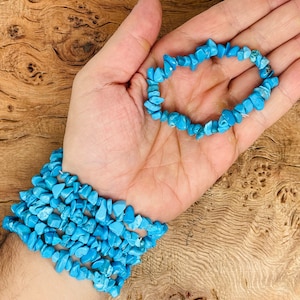 May include: Two turquoise chip bracelets, one worn on the wrist and the other held in the palm of a hand. The bracelets are made of small, irregular turquoise chips.