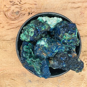 Peut inclure: Gros plan d'un bol rempli de pierres d'azurite rugueuses, bleu foncé et vert.