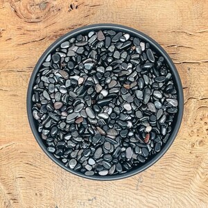 May include: A black bowl filled with small, black and grey tumbled stones.