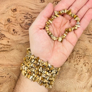 May include: A brown and white gemstone chip bracelet with multiple strands. The bracelet is made of small, irregular shaped chips of gemstone.