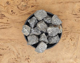 May include: A black bowl filled with small, dark gray, rough-textured rocks.