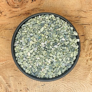 May include: A black bowl filled with green and white speckled gravel.