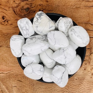 May include: A bowl filled with white howlite tumbled stones. The stones are smooth and have a white and gray marbled pattern.