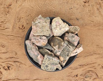 May include: A bowl of pink and grey tumbled stones. The stones are smooth and have a mottled appearance.