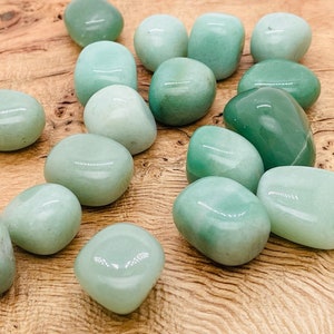 May include: A collection of smooth, light green tumbled stones. The stones are various sizes and shapes, and have a polished, glossy finish.
