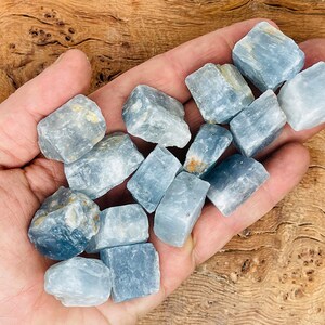 May include: A collection of light blue celestite crystals in various sizes and shapes. The crystals are rough and have a natural, unpolished look.