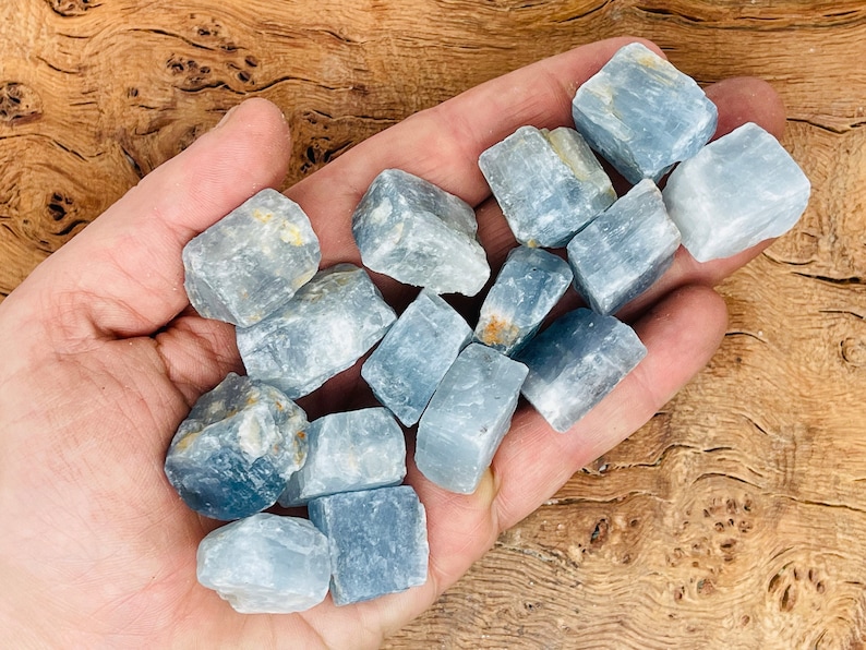 May include: A collection of light blue celestite crystals in various sizes and shapes. The crystals are rough and have a natural, unpolished look.