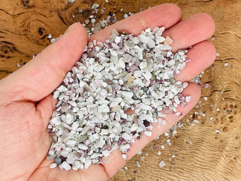 May include: A handful of small, white and pink tumbled stones. The stones are smooth and have a natural, polished look.